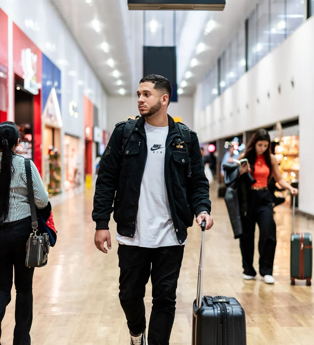 A traveller walking through an airport terminal with a bag