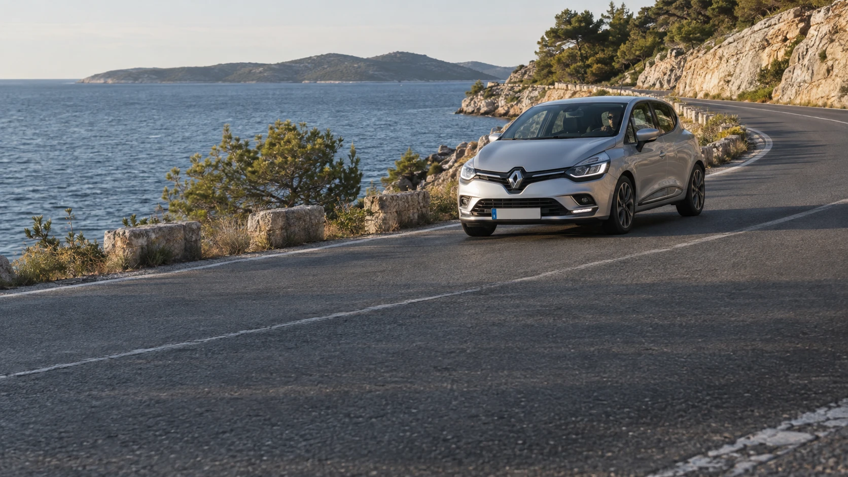 A silver hatchback on a coastal road above the Adriatic