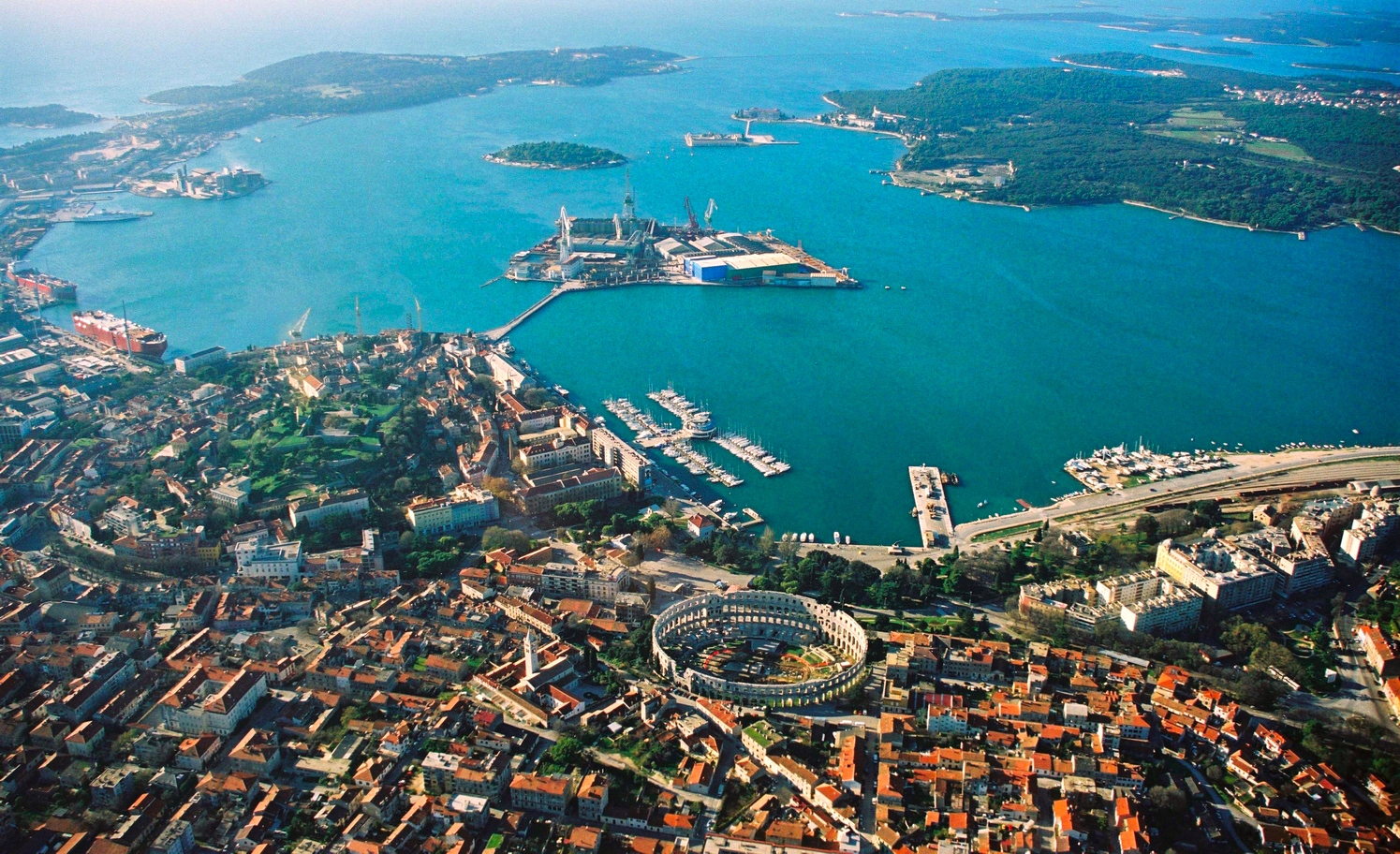 Pula and its harbour from the air, with the Arena near the water
