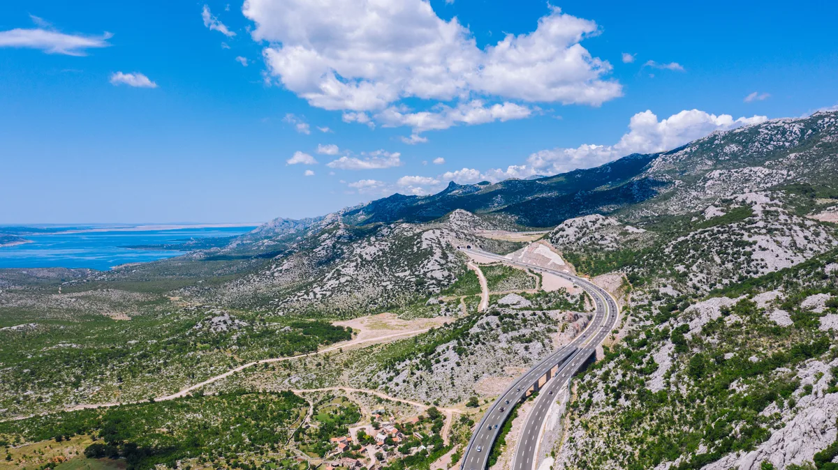 A dual carriageway motorway in Croatia curving through rocky hills towards a tunnel